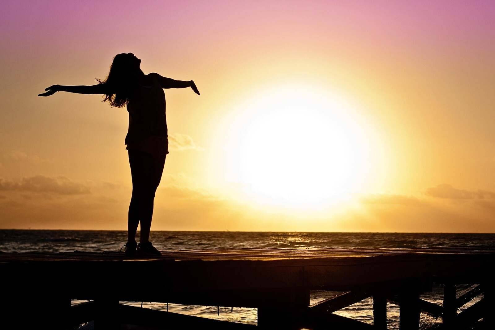 Woman silhouetted at sunset by the sea