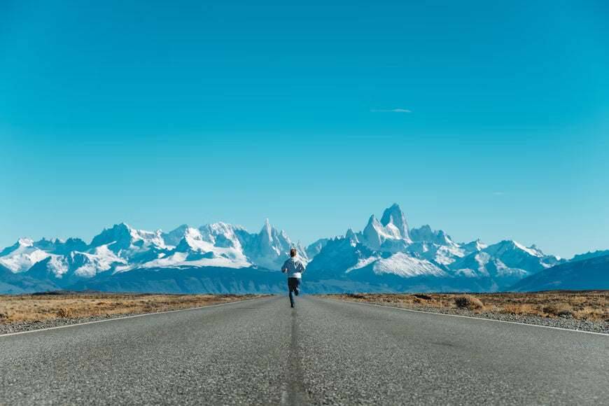 Runner on a road toward snowy mountains